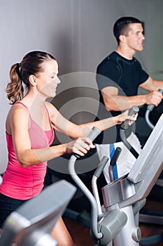 People exercising on elliptical trainer in gym