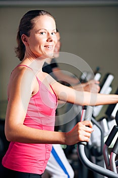 People exercising on elliptical trainer in gym photo