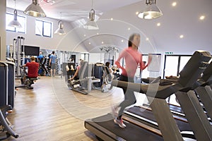 People exercising in a gym, blurred woman runs in foreground