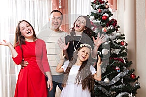 People family, christmas and adoption concept - happy mother, father and children hugging near a Christmas tree at home