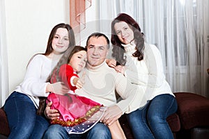 People family, christmas and adoption concept - happy mother, father and children hugging near a Christmas tree at home