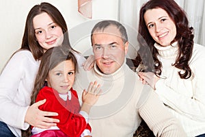 People family, christmas and adoption concept - happy mother, father and children hugging near a Christmas tree at home