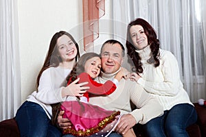 People family, christmas and adoption concept - happy mother, father and children hugging near a Christmas tree at home