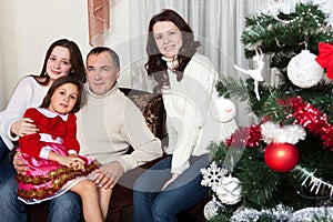 People family, christmas and adoption concept - happy mother, father and children hugging near a Christmas tree at home