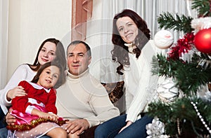People family, christmas and adoption concept - happy mother, father and children hugging near a Christmas tree at home