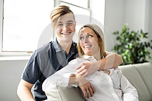 A people and family happy teen boy with mother on sofa at home