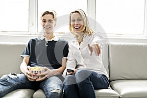 A people and family happy teen boy with mother on sofa at home listening TV