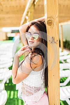 People, fashion, summer and beach concept - happy young woman in summer clothes over swimming pool at beach resort