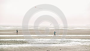 People fly a kite on the seashore .Wadden Sea Coast.Frisian Islands.Fer Island.Germany.Kites and people walking on the