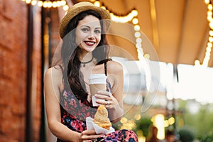 People, food, rest and lifestyle concept. Brunette woman with long hair, wearing summer dress and hat, drinking takeaway coffee an