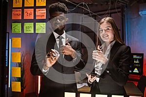 People in formal wear using adhesive notes and writing while standing behind the glass wall