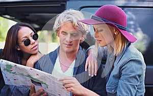 People, friends and map for road trip in search of direction, guide or information of location on a travel journey. Lost