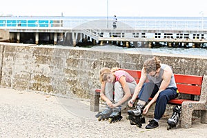 People friends putting on roller skates outdoor.