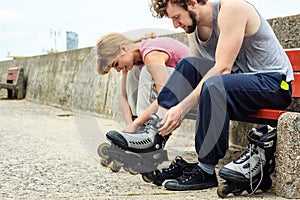 People friends putting on roller skates outdoor.