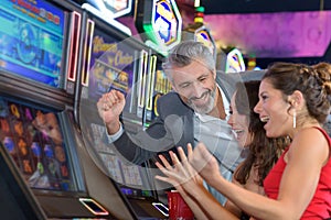 People gambling in casino playing slot machine