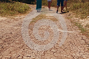 People go along the dry road in cracks in rural areas with droughty climate