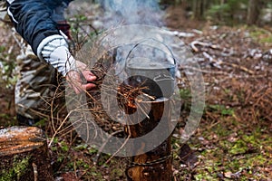 People are going to cook food in a pot on Swedish Fire Log. Burning a Swedish candle, torch in winter evening