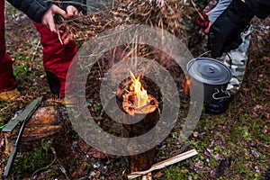 People are going to cook food in a pot on Swedish Fire Log. Burning a Swedish candle, torch in winter evening