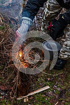 People are going to cook food in a pot on Swedish Fire Log. Burning a Swedish candle, torch in winter evening