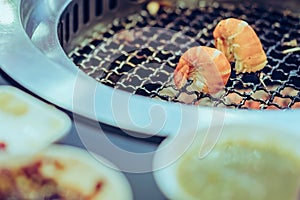 People grilling meat on a smokeless barbecue grill in a restaurant.
