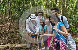 People Group With Backpacks Trekking On Forest Path With Giude Using Cell Smart Phone, Mix Race Young Men And Woman On