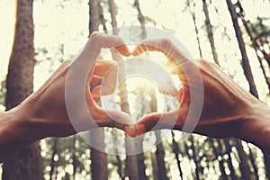 people hand hearts shape with sunshine