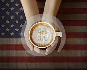 People hand holding cup of coffe with 4th of July message