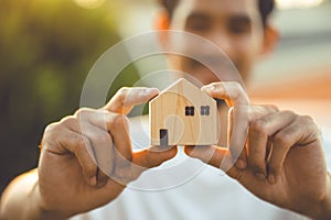 people hand holding miniature wooden house model for banking housing mortgage real estate rent lease home family concept