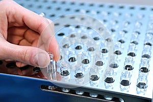 People hand holding a test tube vial sets for analysis in the gas liquid chromatograph. Laboratory assistant inserting laboratory