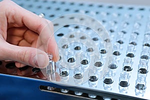 People hand holding a test tube vial sets for analysis in the gas liquid chromatograph. Laboratory assistant inserting laboratory