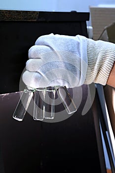 People hand holding a test tube vial sets for analysis in the gas liquid chromatograph. Laboratory assistant inserting laboratory