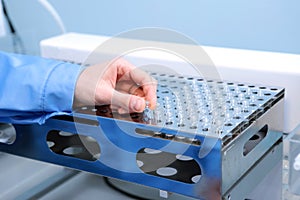 People hand holding a test tube vial sets for analysis in the gas liquid chromatograph. Laboratory assistant inserting laboratory