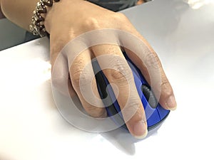 People hand holding and touching blue color computer mouse on white table background