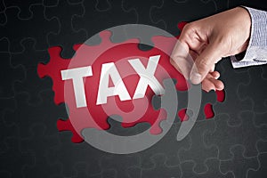 People hand placing puzzle piece with word TAX