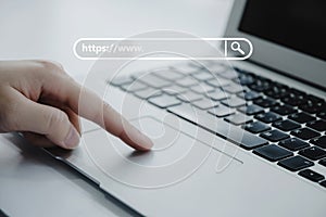 People hand touching touchpad on laptop computer with www search bar graphic on desk at home office