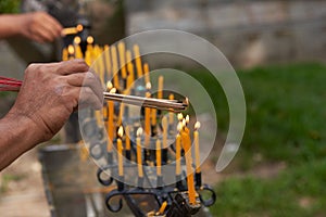 People hands burning incense from candles