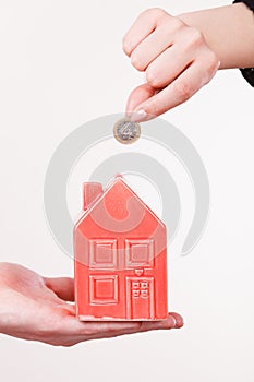 People hands with little house and silver coin.