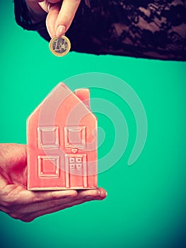 People hands with little house and silver coin.