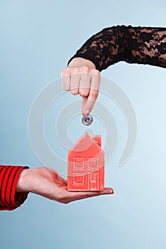 People hands with little house and silver coin.