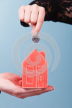 People hands with little house and silver coin.