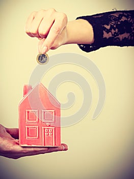 People hands with little house and silver coin.