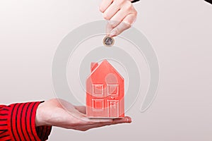 People hands with little house and silver coin.