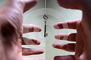 People hands reaching for vintage key hanging on a string. Business success freedom concept concept for aspirations, achievement