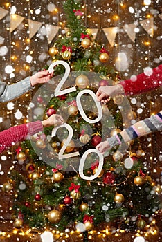 People hands showing 2020 numbers on wooden background - new year holiday concept