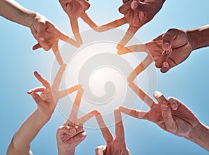 People, hands and star with fingers below in unity, teamwork or community on a blue sky background. Closeup or low angle