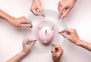 People hands throwing coins in piggy bank for crowdfunding