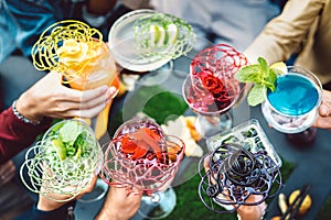 People hands toasting multicolored fancy cocktails - Friends having fun drinking fresh specialties at fashion bar happy hour