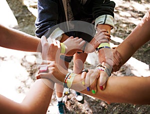 People, hands together and outdoor festival with arm bands for community, teamwork or unity at event. Group of friends