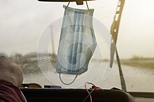 People have gotten into the habit of hanging Covid-19 masks on the rearview mirror of their vehicle`s windshield, foreground and