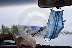 People have gotten into the habit of hanging Covid-19 masks on the rearview mirror of their vehicle`s windshield, foreground and